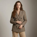 Woman wearing a brown checkered blazer against a plain background