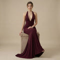 Woman in a burgundy evening gown sitting on a beige chair against a beige background