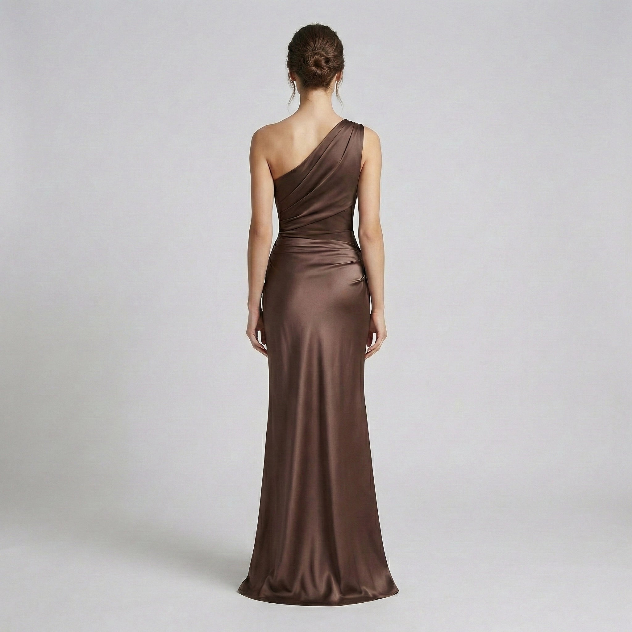 Woman wearing a brown one-shoulder evening gown on a plain background