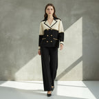 Woman wearing a black and white suit with gold buttons on a gray background