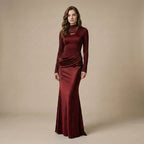 Woman wearing a burgundy evening gown against a beige background