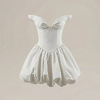 White dress with bow detail on a beige background