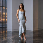 Woman in a light blue dress standing in a modern indoor setting with large windows.