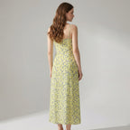 Woman wearing a yellow floral dress against a plain background