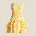 Yellow strapless dress with ruffled layers on a beige background