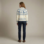 Person wearing a patterned sweater and dark jeans against a plain background
