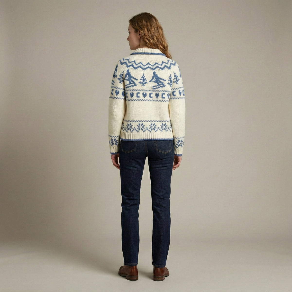 Person wearing a patterned sweater and dark jeans against a plain background