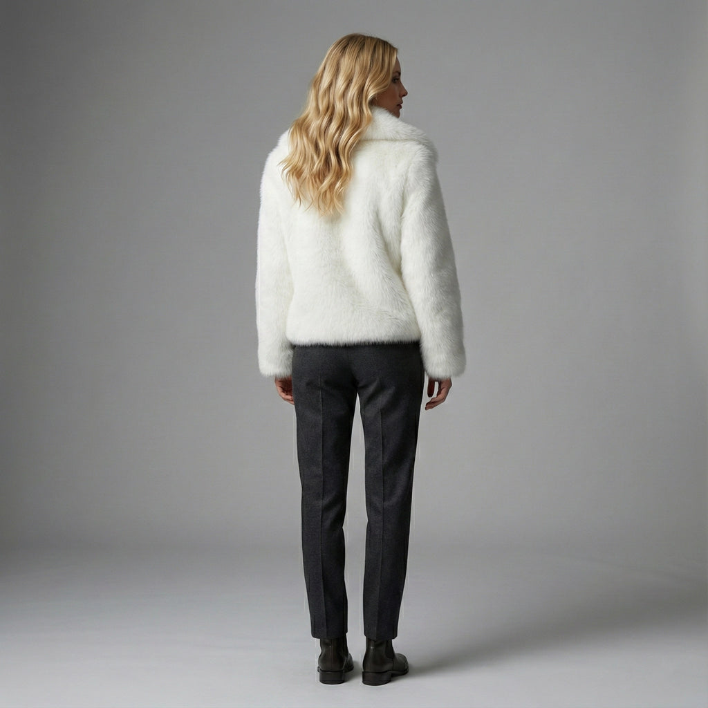 Person wearing a white fluffy sweater and dark pants against a gray background