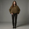 Woman wearing a brown jacket and black pants against a gray background