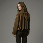 Woman wearing a brown jacket and black pants against a gray background