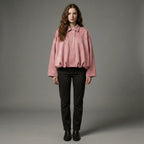 Woman wearing a pink shirt and black pants against a gray background