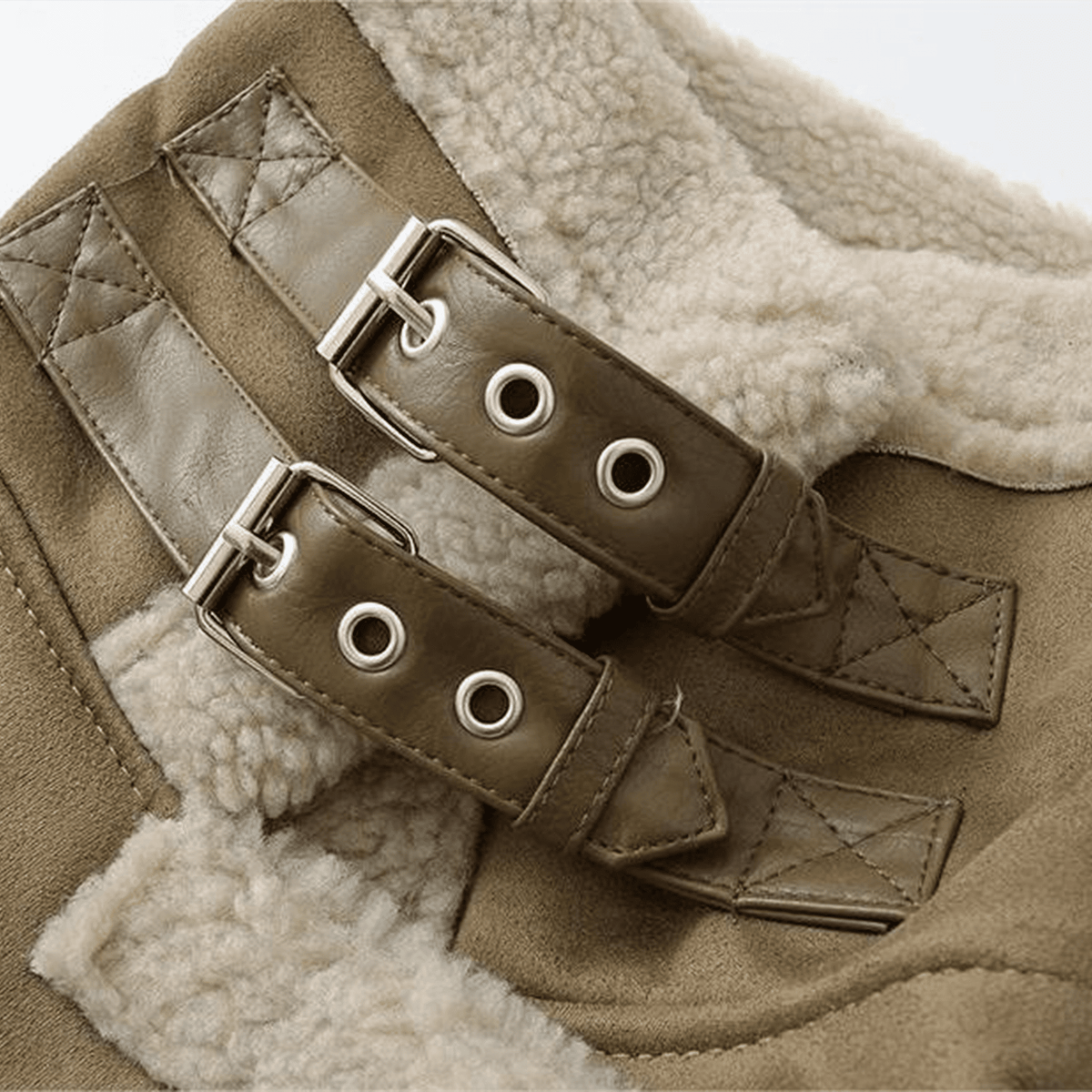 Close-up of a brown leather belt with metal buckles on a textured fabric background