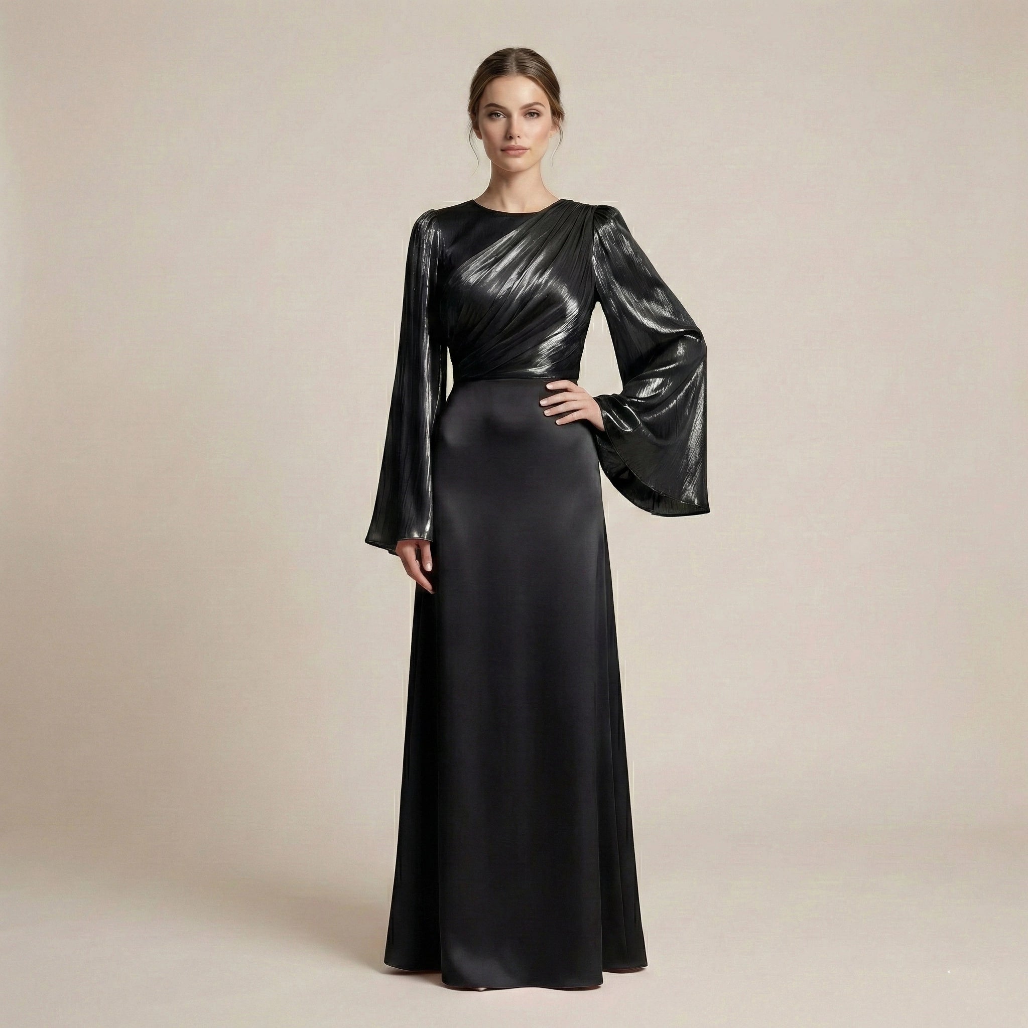 Woman wearing a black evening gown with metallic sleeves on a beige background