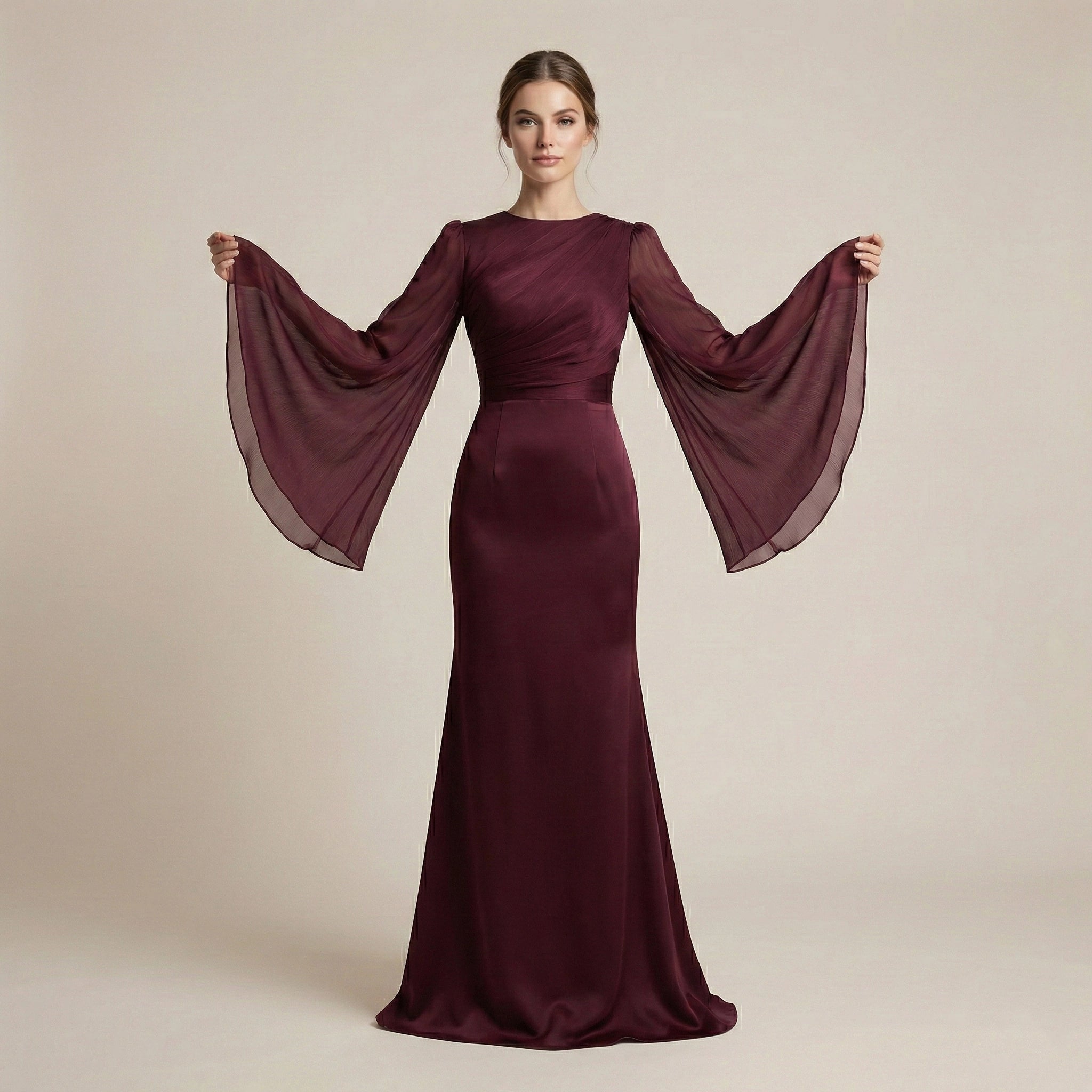 Woman wearing a burgundy evening gown with sheer sleeves against a beige background