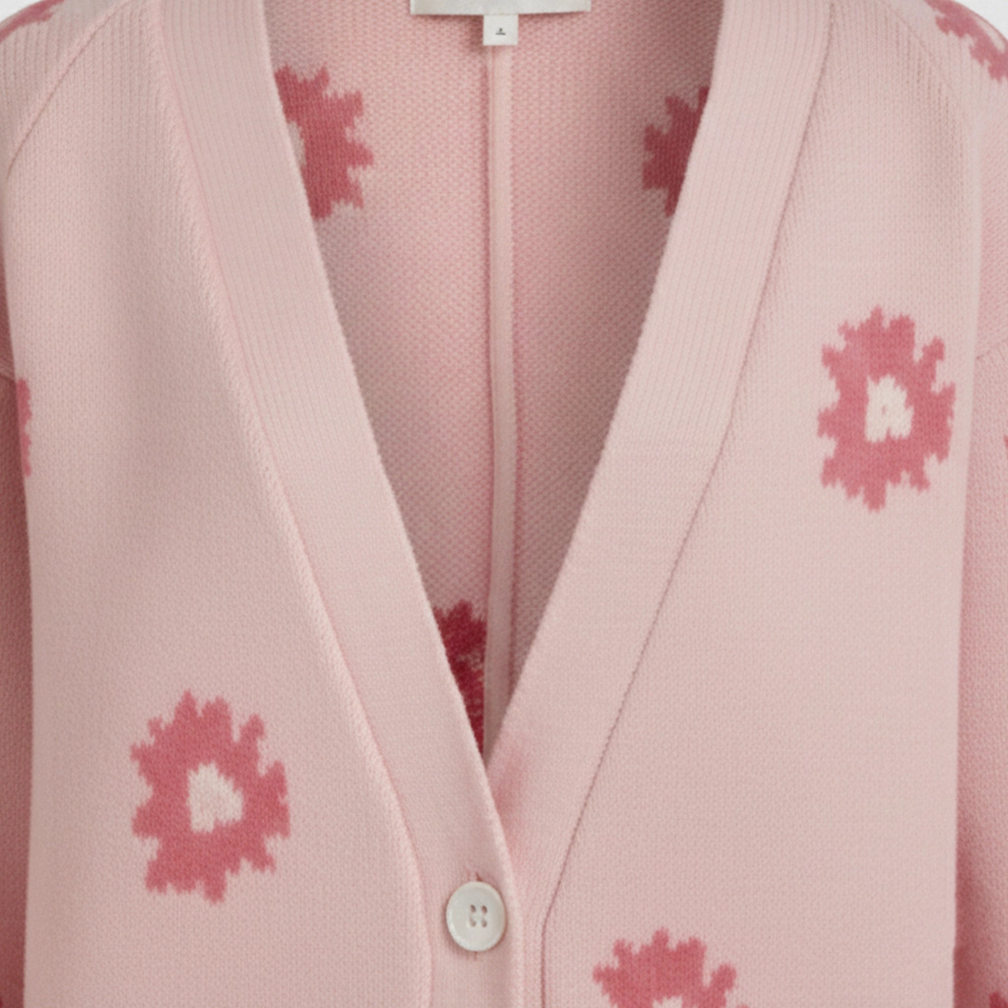 Pink cardigan with floral patterns on a matching fabric background