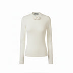 White long-sleeve top with floral details on a white background