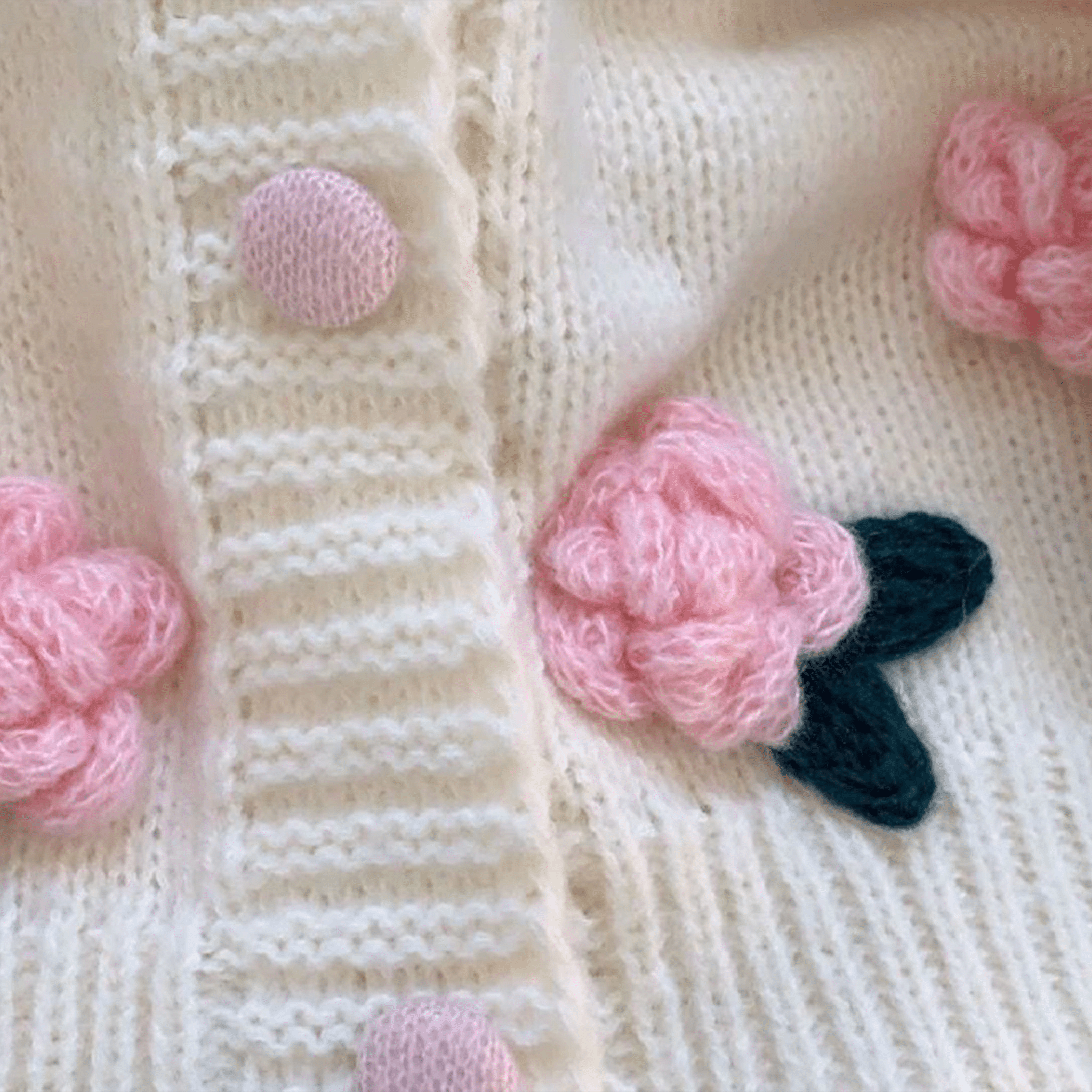 Close-up of a knitted fabric with pink floral patterns and buttons.