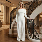 Woman in a white outfit standing in a luxurious interior setting with a staircase.