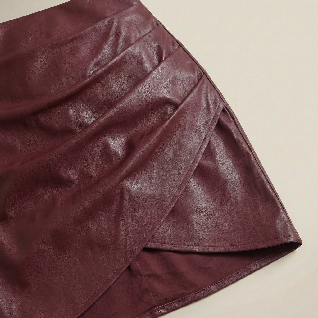 Close-up of a maroon leather skirt on a beige background