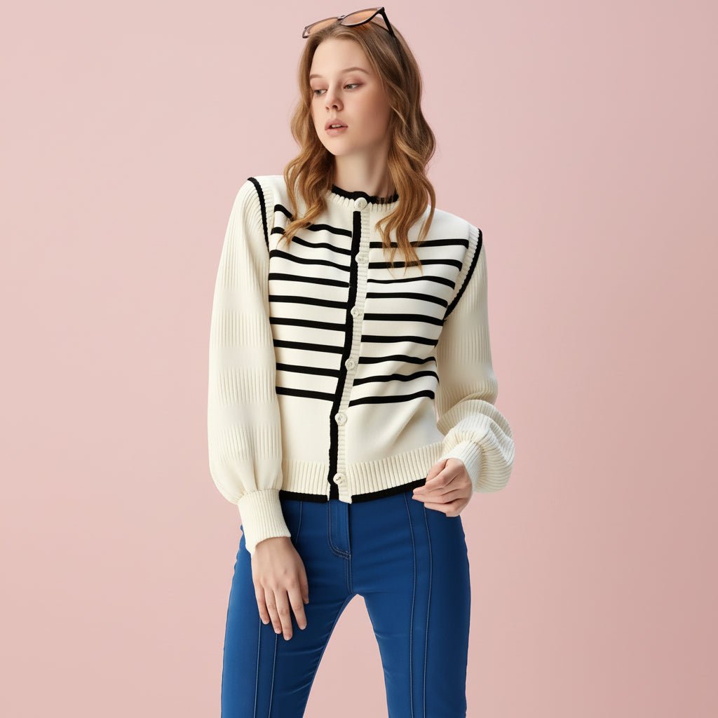 Woman wearing a cream cardigan with black striped pattern and blue pants on a light gray background