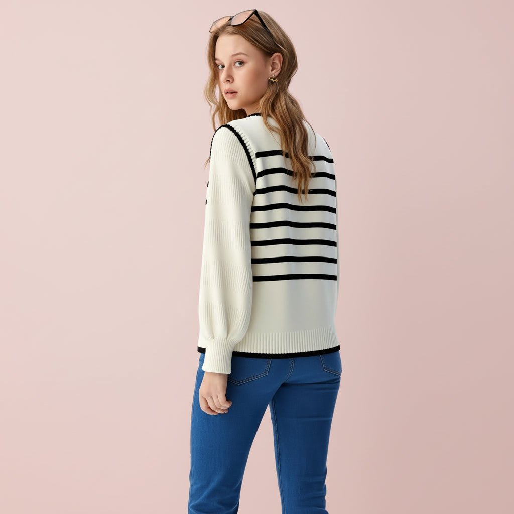 Person wearing a white sweater with black stripes and blue jeans on a light gray background