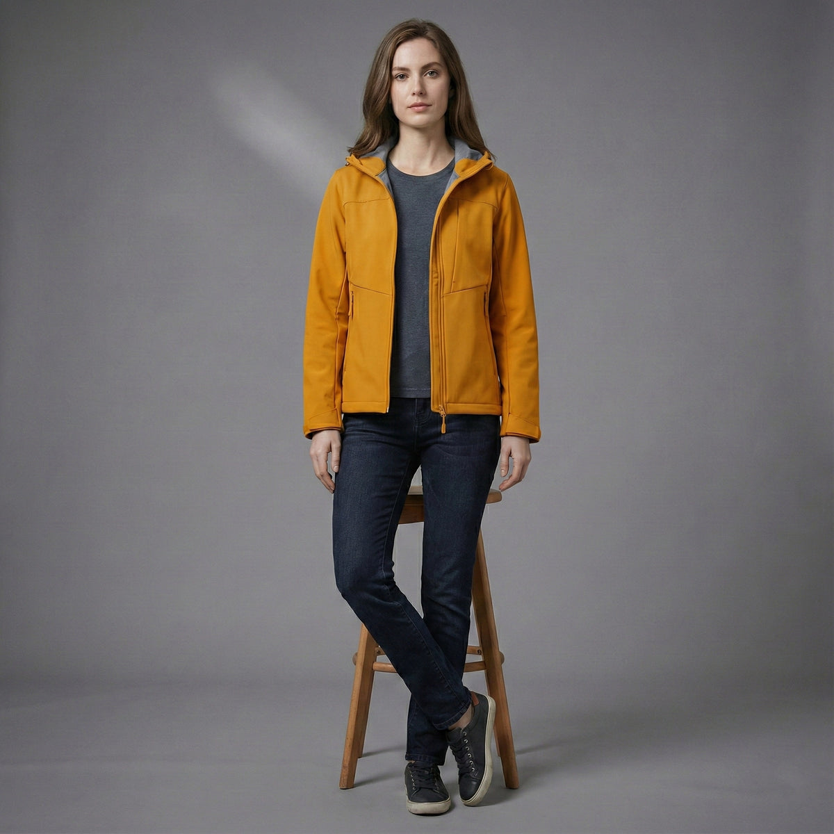 Woman wearing a mustard yellow jacket on a gray background