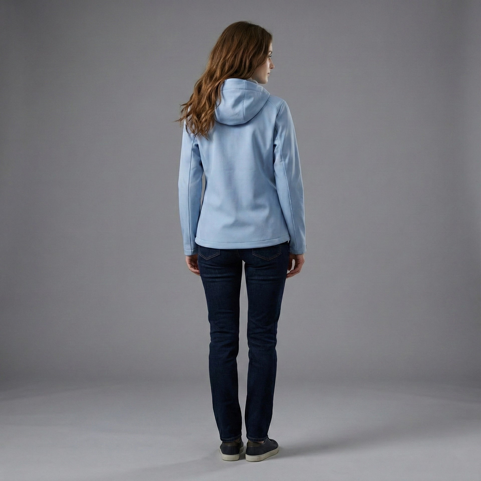 Person wearing a light blue hoodie and dark jeans on a gray background