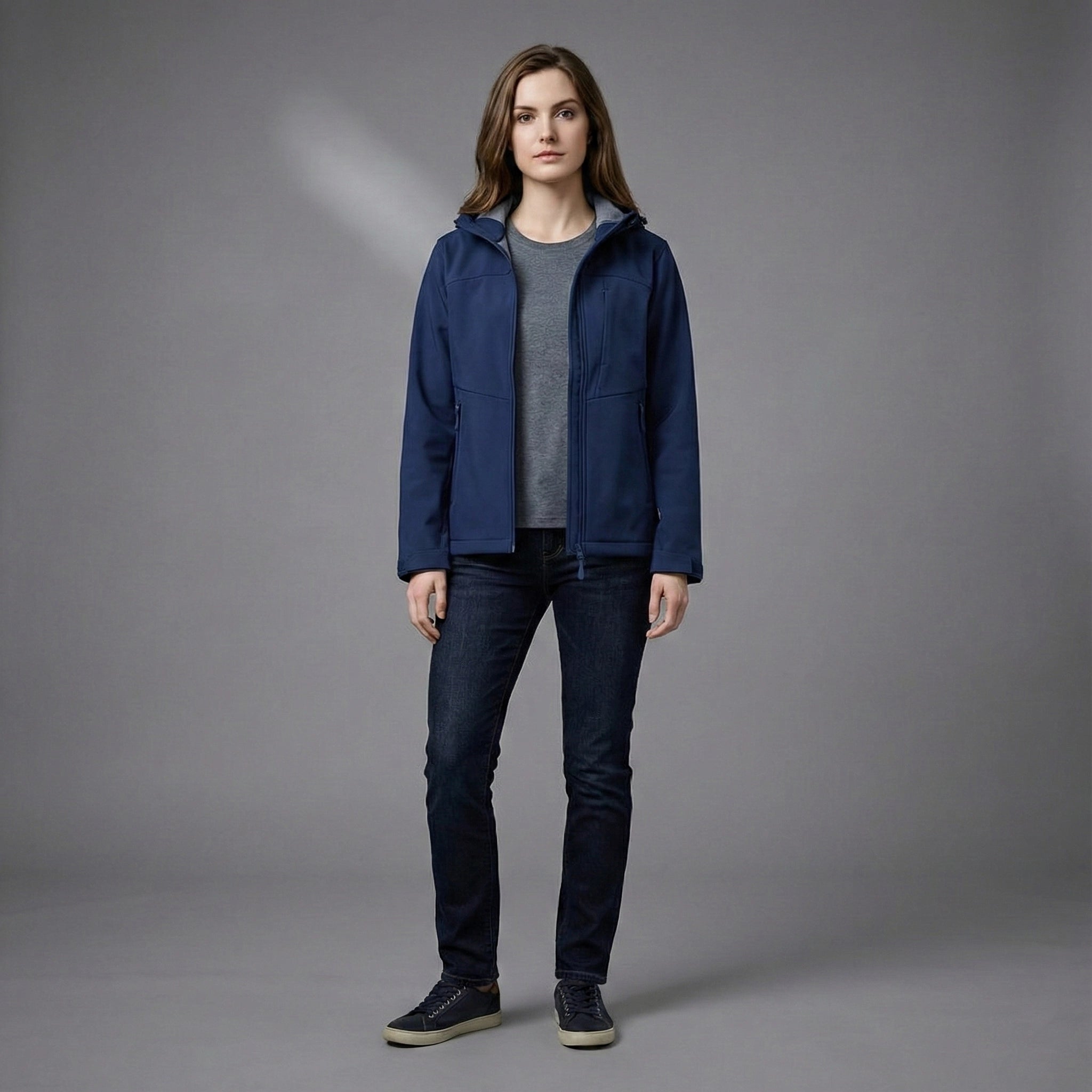 Person wearing a blue jacket and dark jeans on a gray background