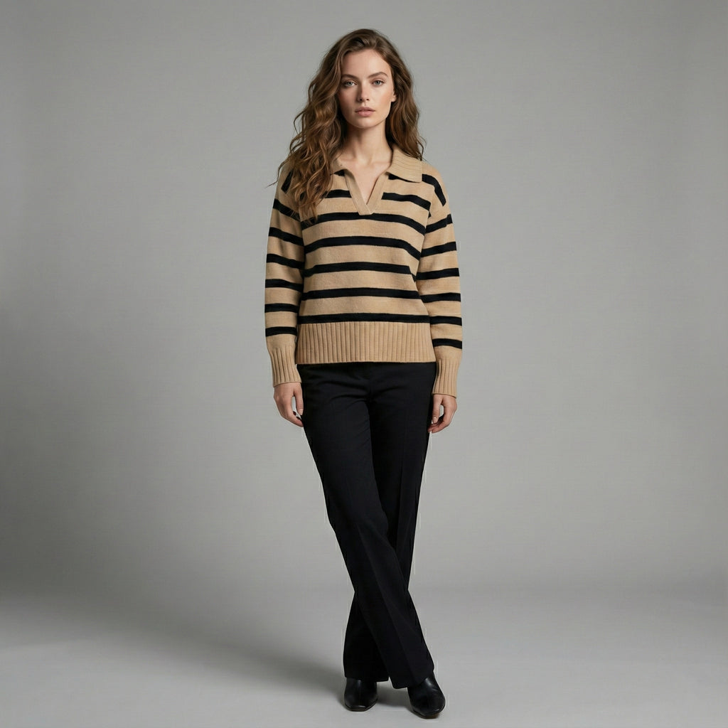 Woman wearing a beige and black striped sweater with black pants on a gray background