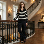 Woman in a black and white striped sweater standing in an elegant interior setting.