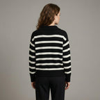Person wearing a black and white striped sweater against a gray background