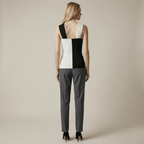 Woman wearing a black and white geometric top with gray pants on a beige background