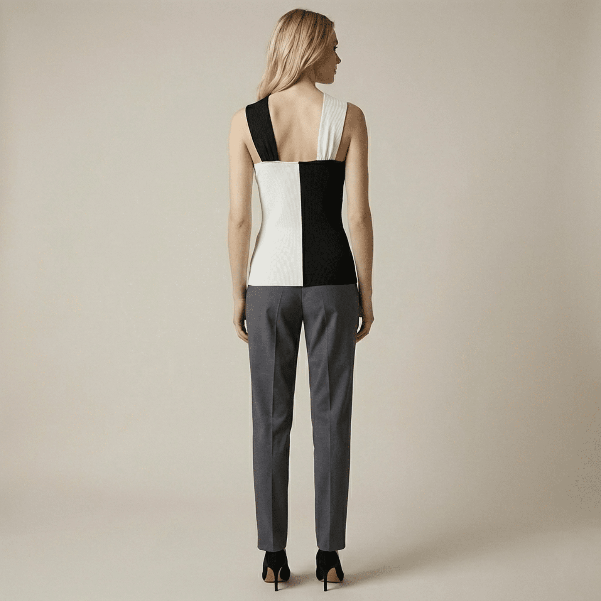 Woman wearing a black and white geometric top with gray pants on a beige background