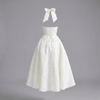 White halter-neck dress with a bow on a gray background