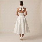 White wedding dress with a bow detail on a plain background