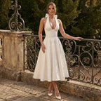 Woman in a white dress standing on a stone path with decorative railing.