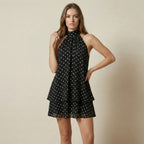 Woman wearing a black dress with white polka dots on a beige background