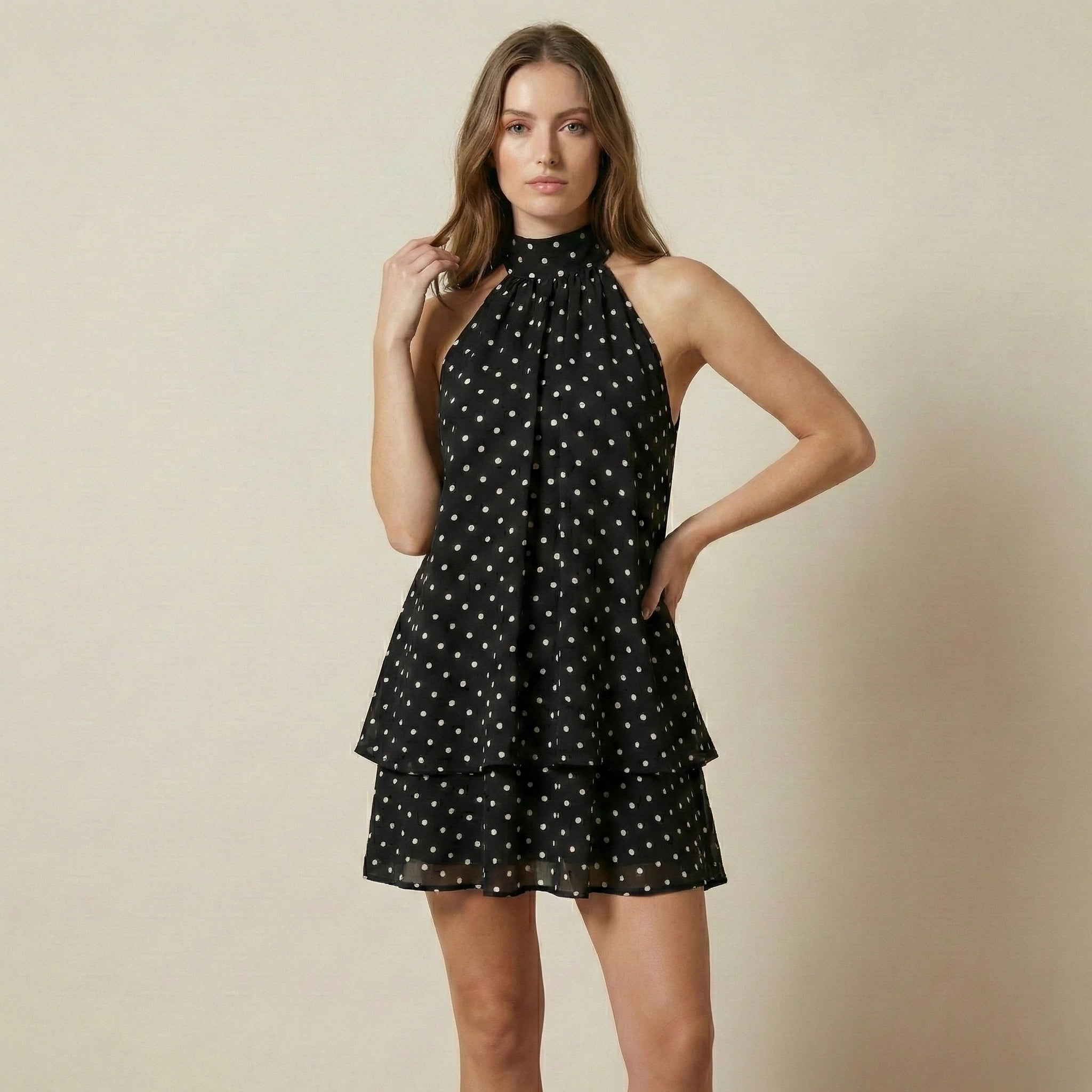 Woman wearing a black dress with white polka dots on a beige background