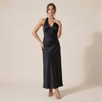 Woman wearing a black satin dress against a beige background