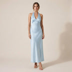 Woman wearing a light blue halter neck dress against a beige background