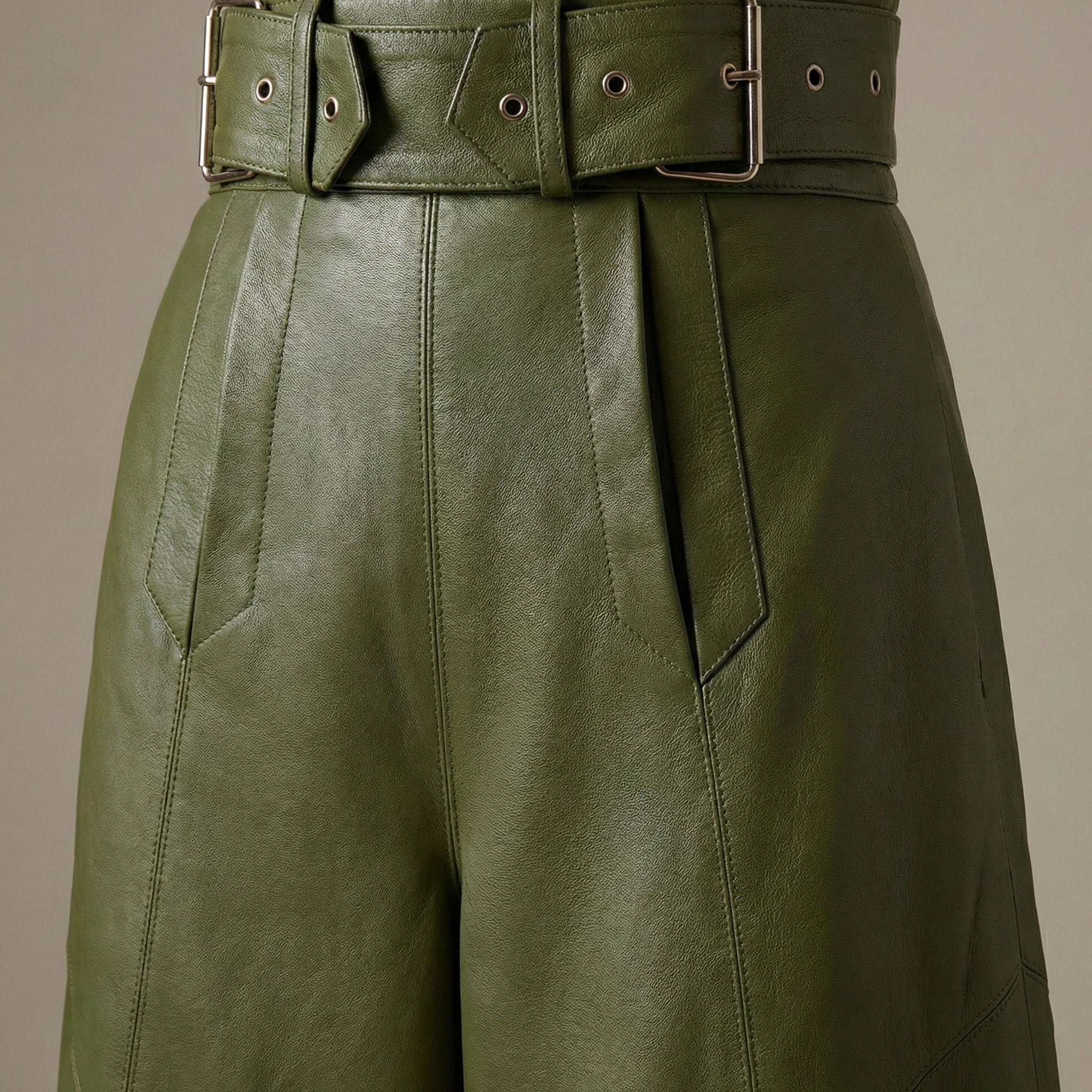 Green leather pants with a belt on a beige background