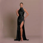 Woman wearing a black evening gown with a high slit on a beige background