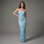 Woman wearing a strapless floral gown against a gray background