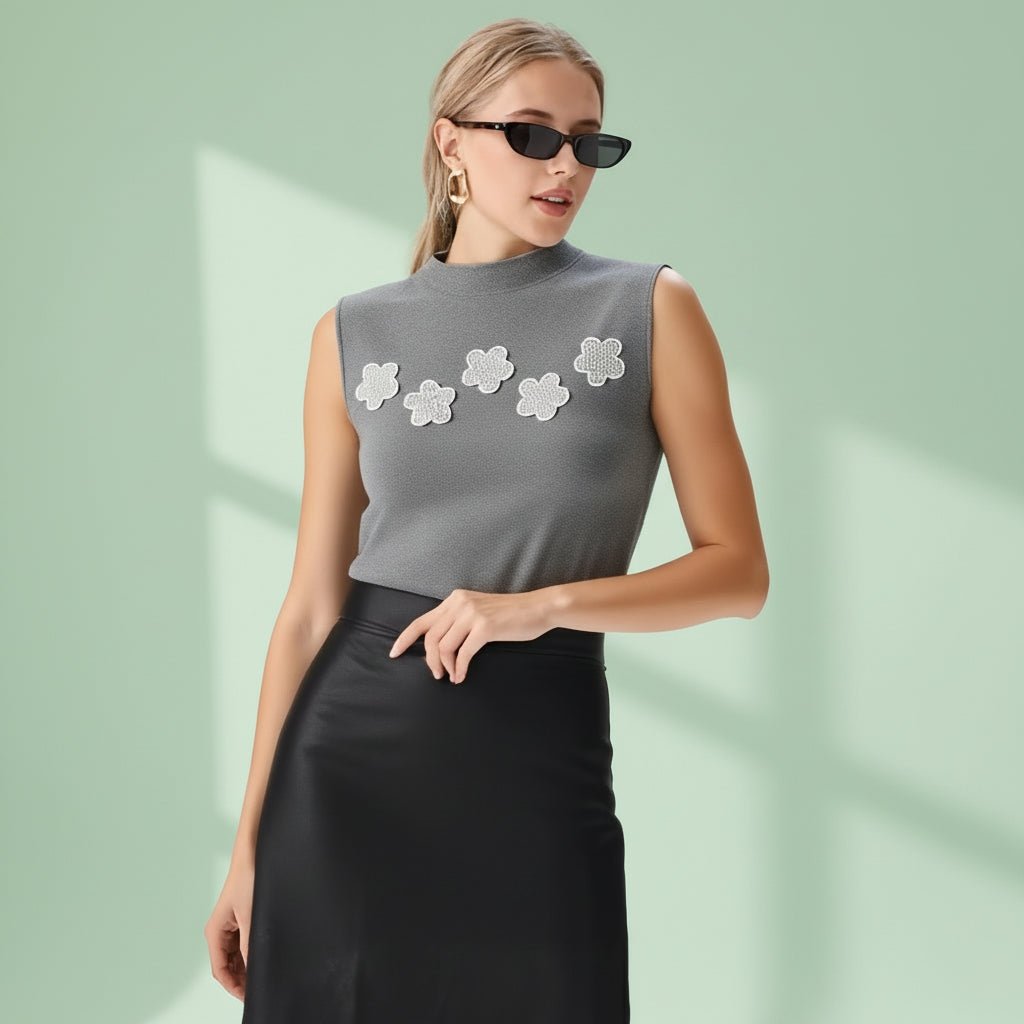 Woman wearing a gray sleeveless top with floral designs and a black skirt on a white background