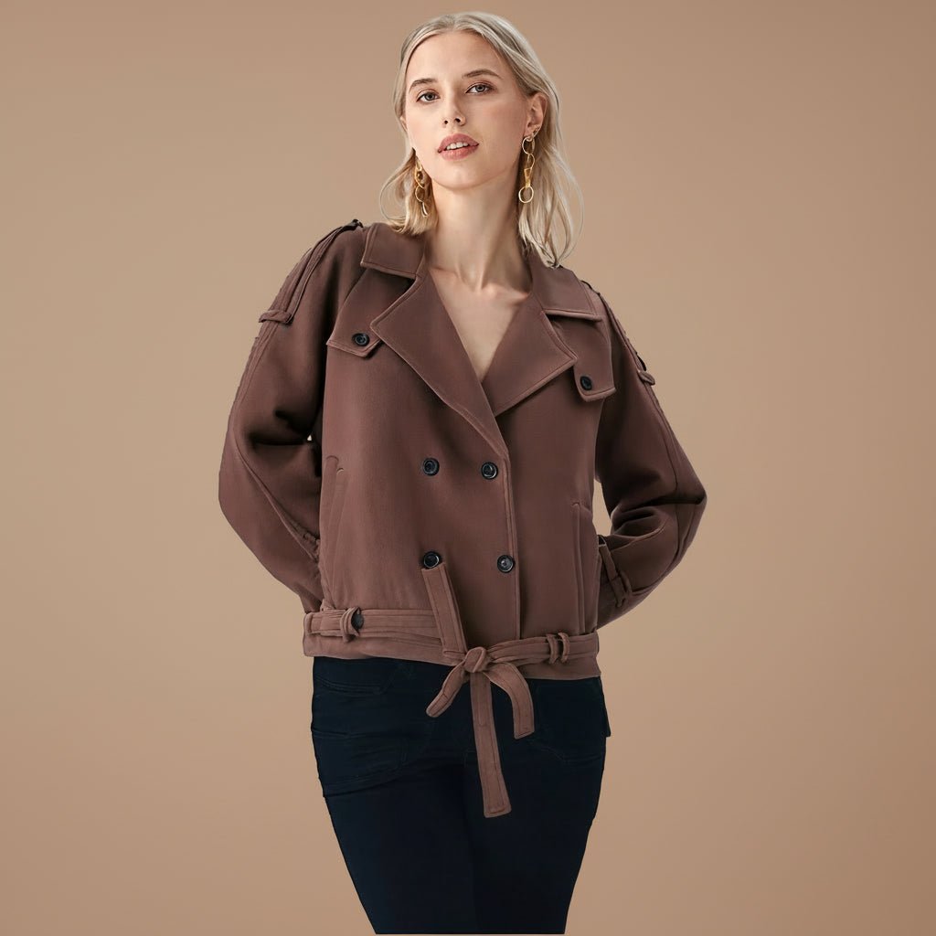 Person wearing a brown coat and black pants against a beige background