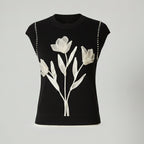 Black sleeveless top with white floral design on a light gray background