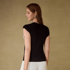 Woman wearing a black top with cut-out shoulders against a beige background