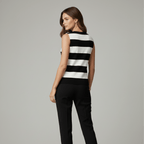 Woman wearing a black and white striped sleeveless top and black pants on a gray background