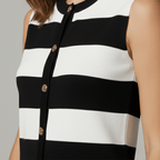 Black and white striped sleeveless top with gold buttons on a neutral background