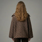 Person wearing a brown checkered coat against a plain background